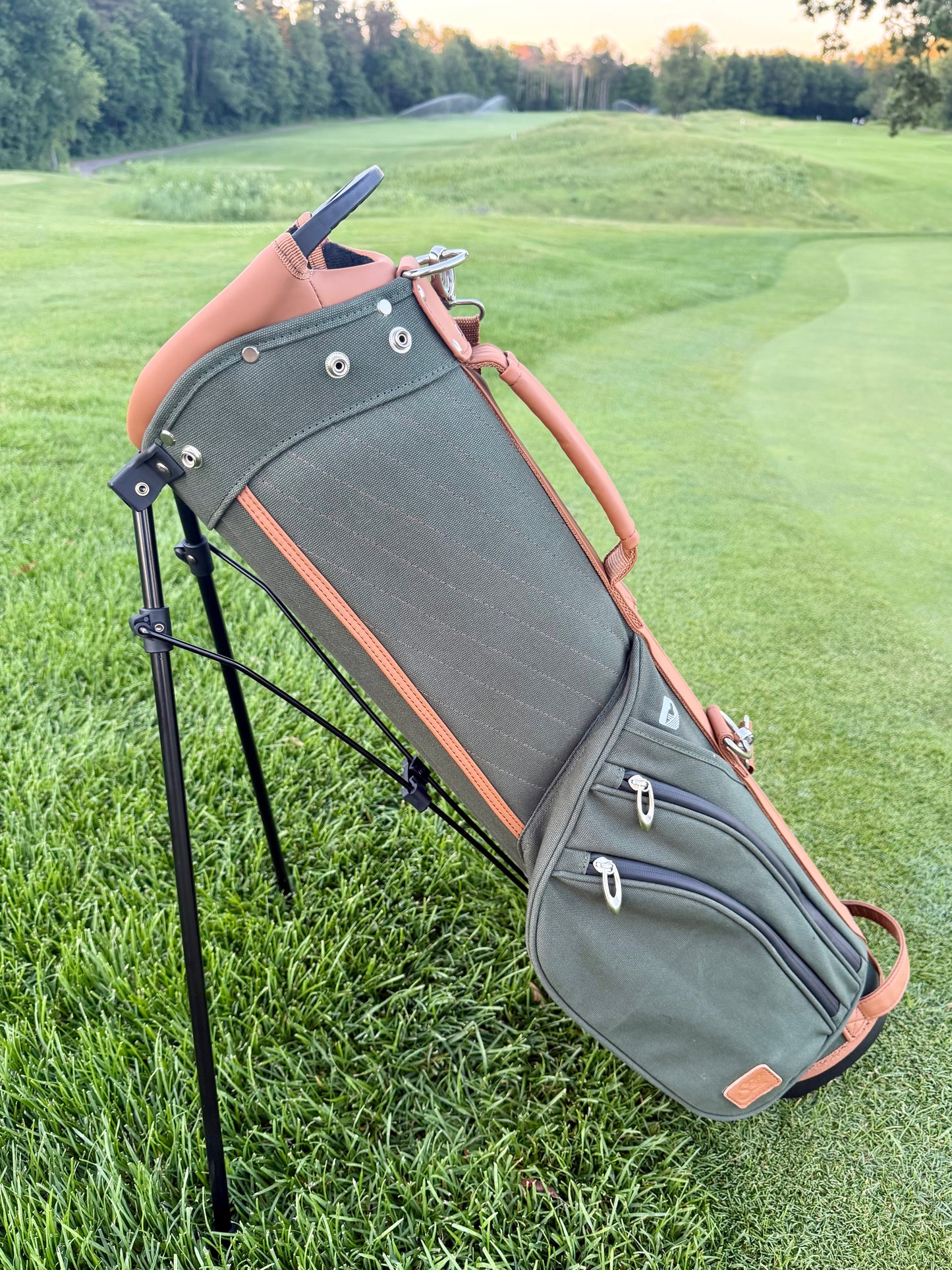Green golf bag with stand on a grassy field
