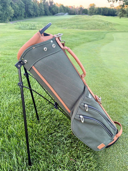 Green golf bag with stand on a grassy field